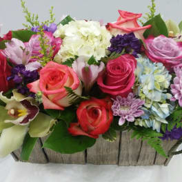 Mixed bouquet of roses, hydrangeas, and orchids in a rustic wooden basket