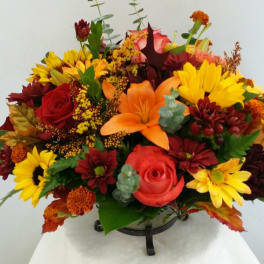 Mixed bouquet with red, yellow, and orange flowers in a low holder
