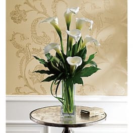 White calla lilies in a tall glass vase on a round table