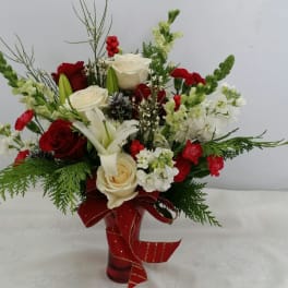 Red and white floral arrangement in a red vase with a ribbon