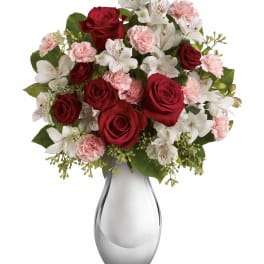 Red roses, pink carnations, and white alstroemeria in a glass vase