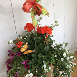 Mixed potted flowers in a metal container with a large ribbon bow