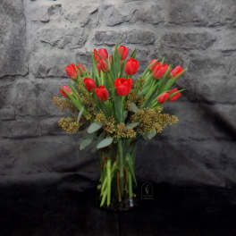 Bouquet of red tulips with greenery against a stone backdrop