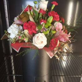 Mixed bouquet of red, white, and pink flowers in a black hatbox