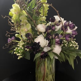 Bouquet of purple and white flowers in a glass vase with curly branches