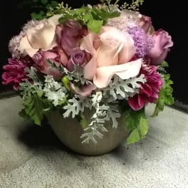 Mixed pink and white roses in a round vase with silver foliage