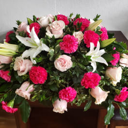 Large floral casket spray with pink roses, white lilies, and hot pink carnations
