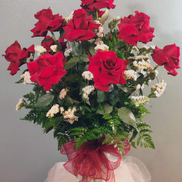 Red roses arranged in a clear glass vase with white filler flowers