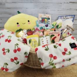 Gift basket with a plush lemon, cherry blanket, and assorted self-care items