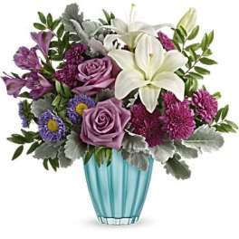 Purple and white flower arrangement in a blue glass vase