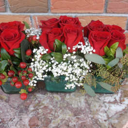 Red roses arranged in three small glass containers with white filler flowers