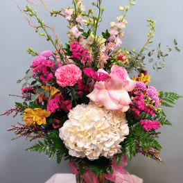 Mixed pink and cream bouquet in a glass vase with a pink ribbon