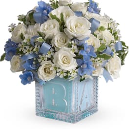 White roses and blue flowers in a glass cube vase