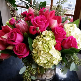 Bouquet of hot pink roses, amaryllis, and pale hydrangeas in a glass vase