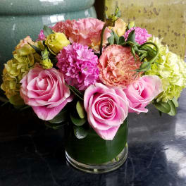 Pink roses and mixed blooms arranged in a glass vase