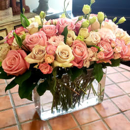 Large bouquet of pink and cream roses in a clear rectangular vase