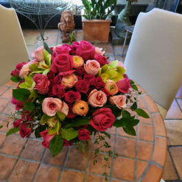 Round bouquet of pink and red roses with green orchids on a table