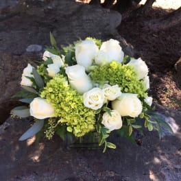 White roses and green hydrangeas in a low square vase