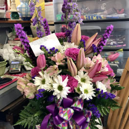 Pink and white mixed bouquet in a glass vase with purple ribbon
