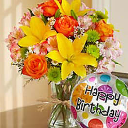 Bright mixed bouquet in a glass vase with a birthday balloon
