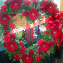 Red rose and gerbera daisy wreath with a ribbon banner
