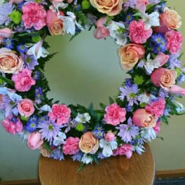 Circular floral wreath with pink roses and purple daisies
