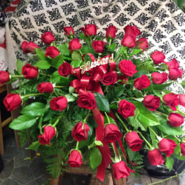 Large bouquet of red roses with a red ribbon and gold topper