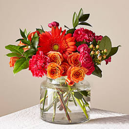 Orange and pink flower arrangement in a clear glass vase