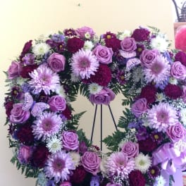 Purple floral wreath on an easel with roses and daisies