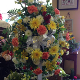 Large standing floral spray with yellow, white, orange, and red blooms
