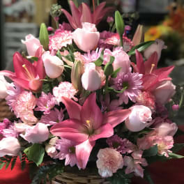Pink lilies, roses, and carnations in a wicker basket