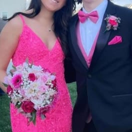 Teen couple in formalwear, one holding a pink and white bouquet