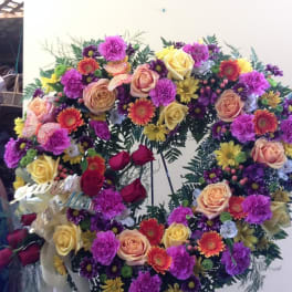 Large circular floral wreath with roses, carnations, and daisies