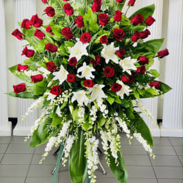 Large standing arrangement of red roses and white lilies with cascading white flowers