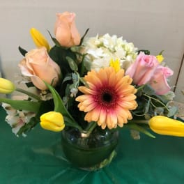 Mixed bouquet with roses, tulips, and a gerbera daisy in a glass vase