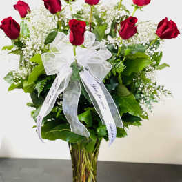 Red roses in a clear glass vase with a white ribbon bow