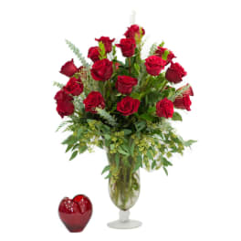 Red roses in a glass vase with a red heart-shaped candle holder