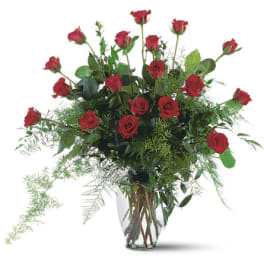 Red roses arranged in a clear glass vase with airy greenery