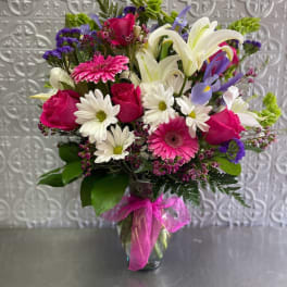 Mixed bouquet of pink, white, and purple flowers in a glass vase