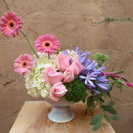 Pink roses and gerbera daisies in a pedestal vase