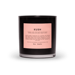 Black scented candle in a glass jar with a pink label