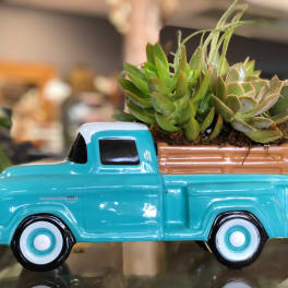 Succulents arranged in a turquoise ceramic truck planter