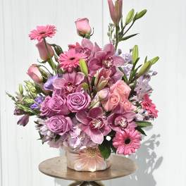 Pink roses, orchids, and gerbera daisies arranged in a ceramic vase
