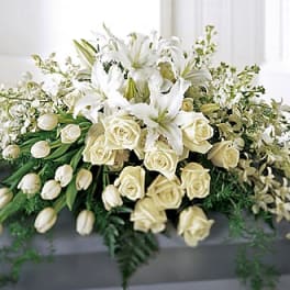 White lilies and cream roses arranged in a low floral display