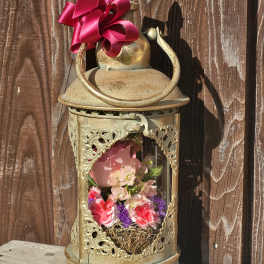 Decorative lantern with pink and purple flowers inside and a magenta ribbon bow on top