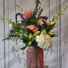 Pink roses and white hydrangea in a mauve vase