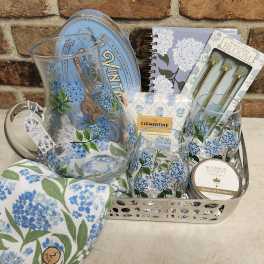 Gift basket with floral-print glassware, notebook, candle, and napkins