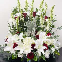 Large floral arrangement with white lilies, red roses, and a clear glass vase