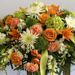 Orange, white, and green floral spray with ribbon accents