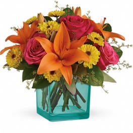 Orange lilies and pink roses in a turquoise glass vase